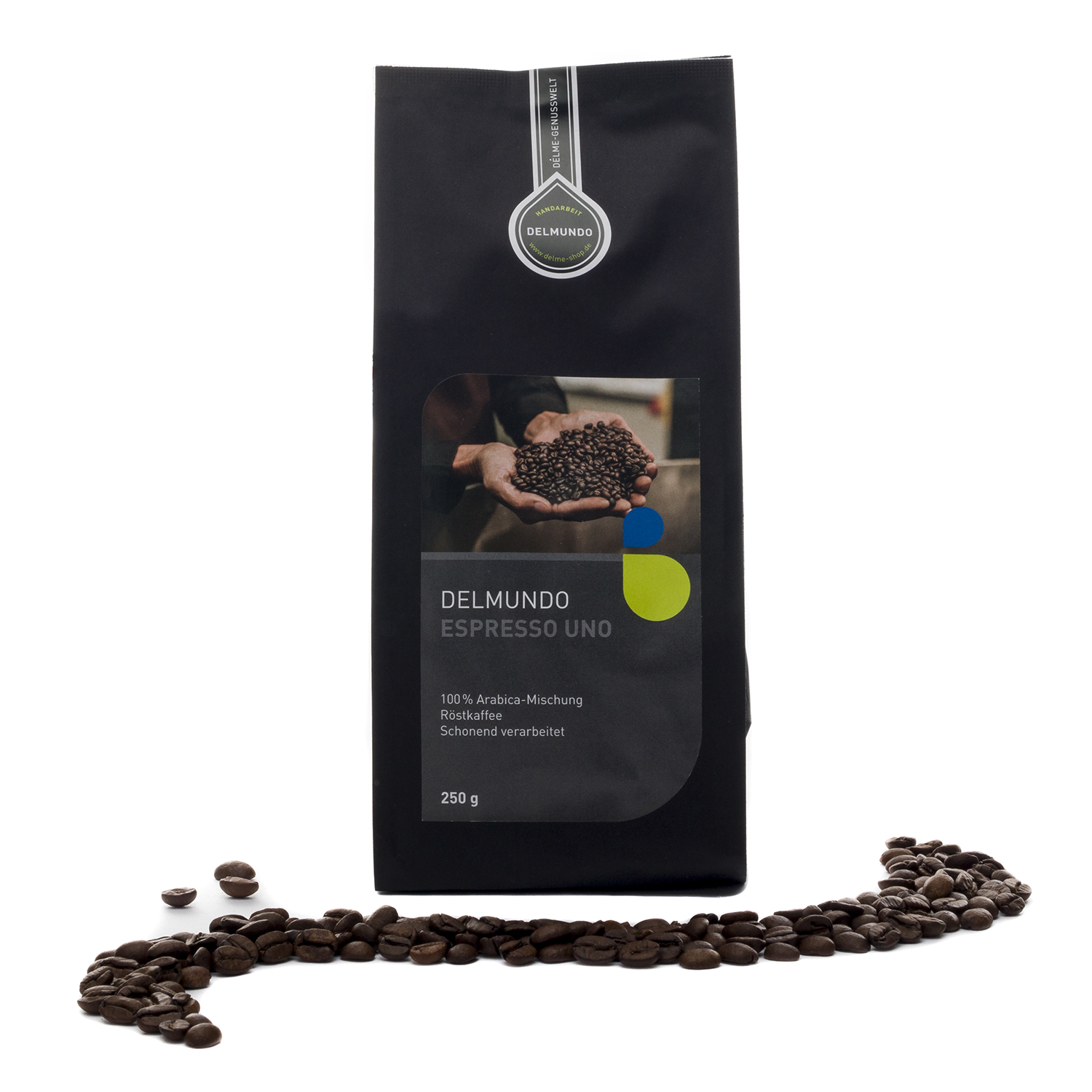 Eine schwarze Papiertüte mit Kaffeebohnen darin. Auf dem Etikett ist ein Bild, auf dem eine große Menge an Kaffeebohnen in zwei Händen gehalten werden. Vor der Tüte liegen Kaffeebohnen verstreut.