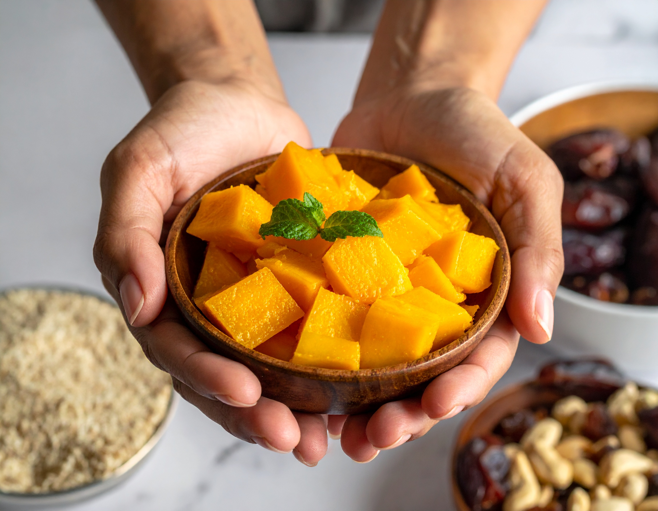 Holzschale mit Mangostückchen, die von 2 Händen gehalten wird - KI-generiert