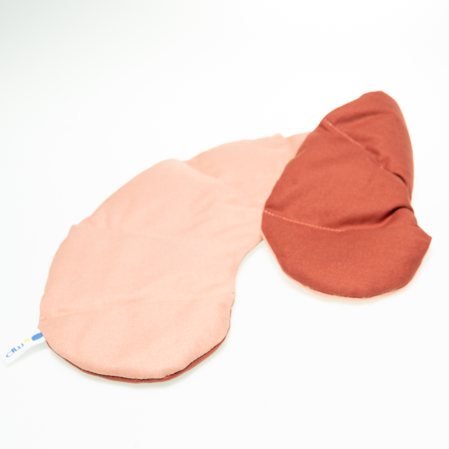 Das flache Körnerkissen in Hörnchenform ist auf der einen Seite ganzflächig rosé und auf der anderen Seite ganzflächig terracottafarben. Damit die Körner nicht durcheinanderfallen, sind sie durch Nähte separiert.