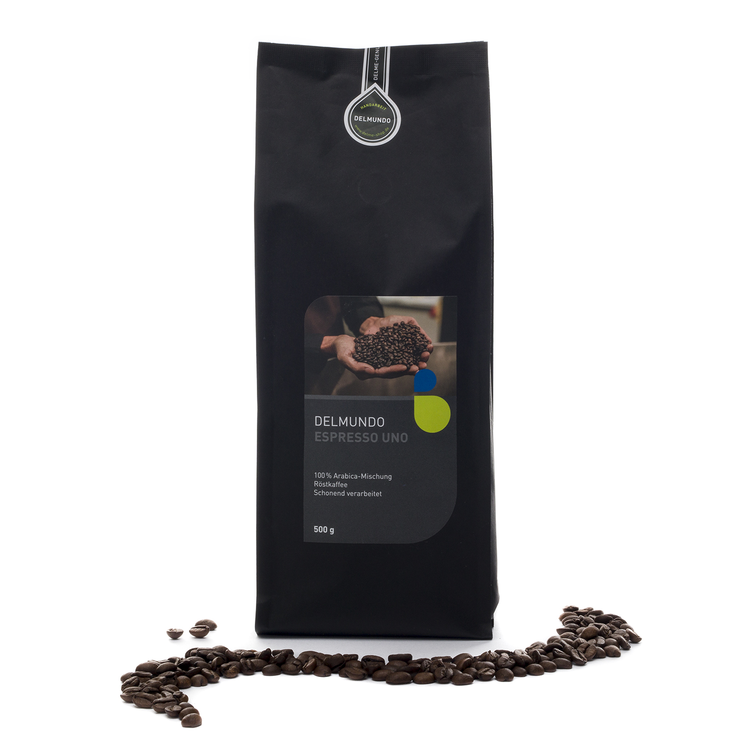 Eine schwarze Papiertüte mit Kaffeebohnen darin. Auf dem Etikett ist ein Bild, auf dem eine große Menge an Kaffeebohnen in zwei Händen gehalten werden. Vor der Tüte liegen Kaffeebohnen verstreut.