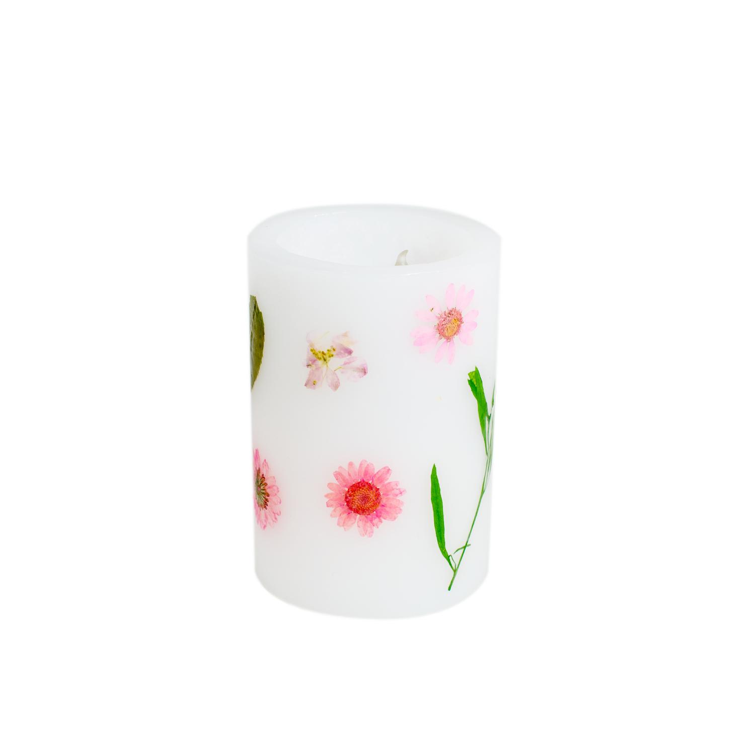 Rundes weißes Windlicht mit rosa Blüten und grünen Blättern.